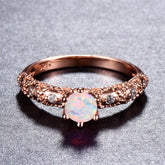 Elegant rose gold ring featuring a round opal stone, adorned with sparkling cubic zirconia accents.